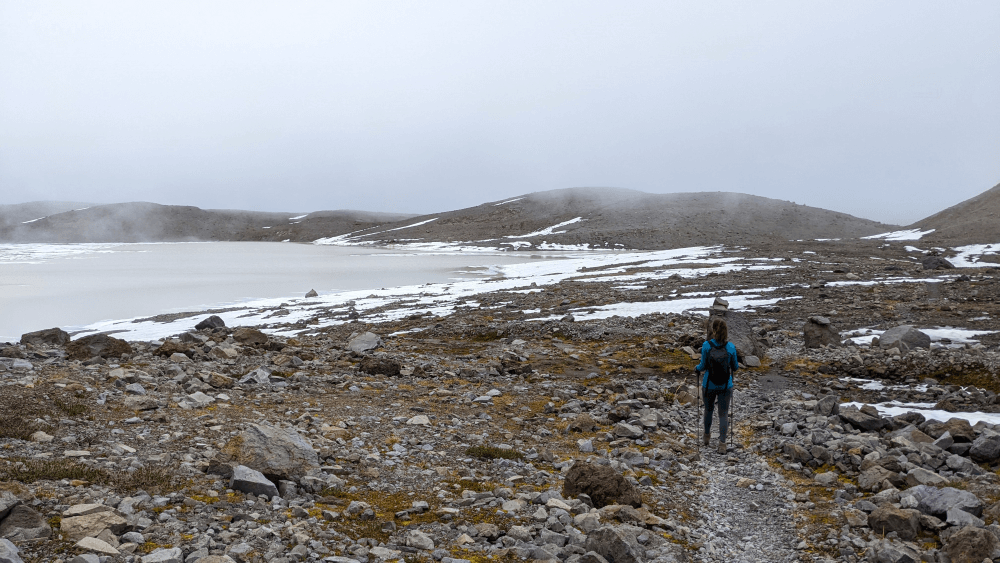 hiker walking next to glacial lake below Opal Cone